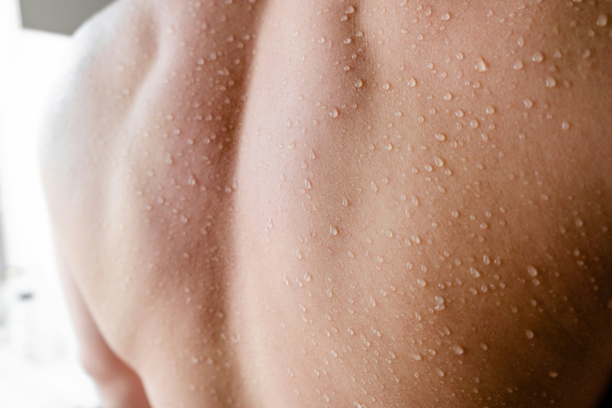 A caucasian young man's back with water drops
